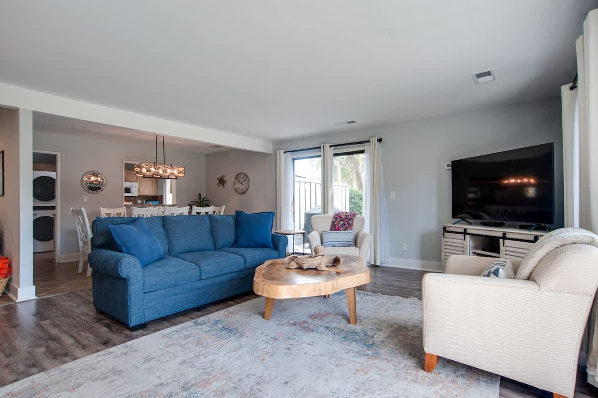 Your open-concept living space features a vibrant blue sofa, cozy seating, and large TV for relaxing after exploring the area.