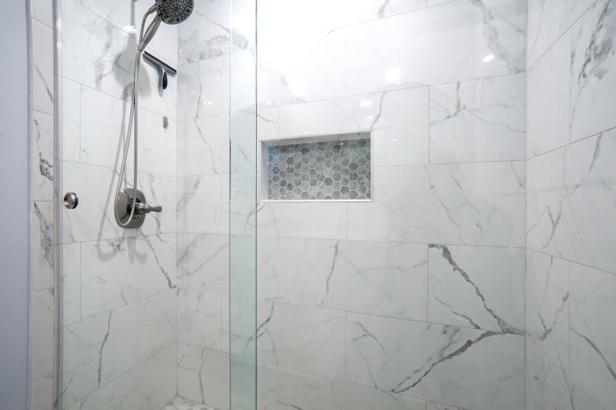 Step into your luxurious marble shower with elegant hexagonal tile niche and premium rainfall showerhead for a spa-like experience.