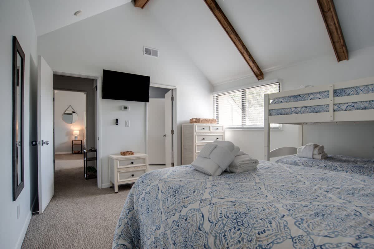 Relax in your coastal bedroom with charming bunk beds and rustic beams overhead, perfect for family getaways.