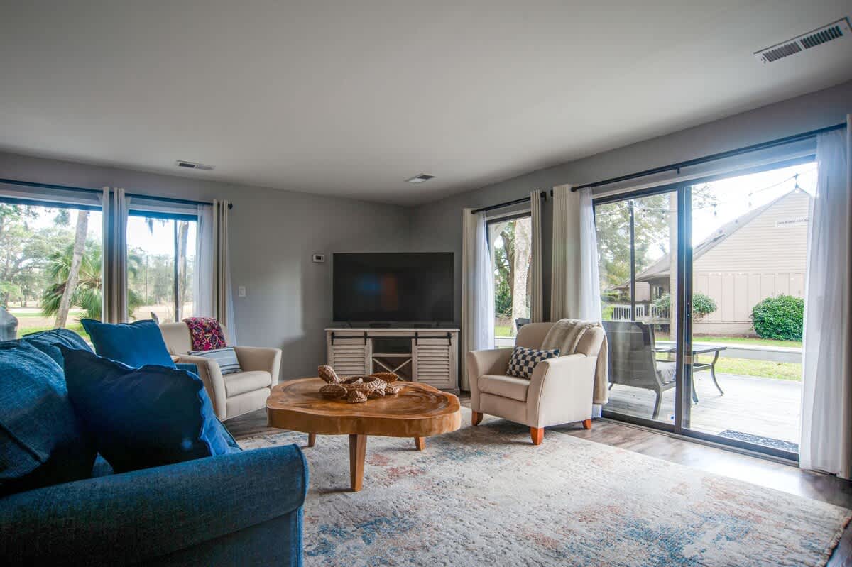 Sink into plush blue sofas and unwind in your bright living space, where large windows frame peaceful neighborhood views.