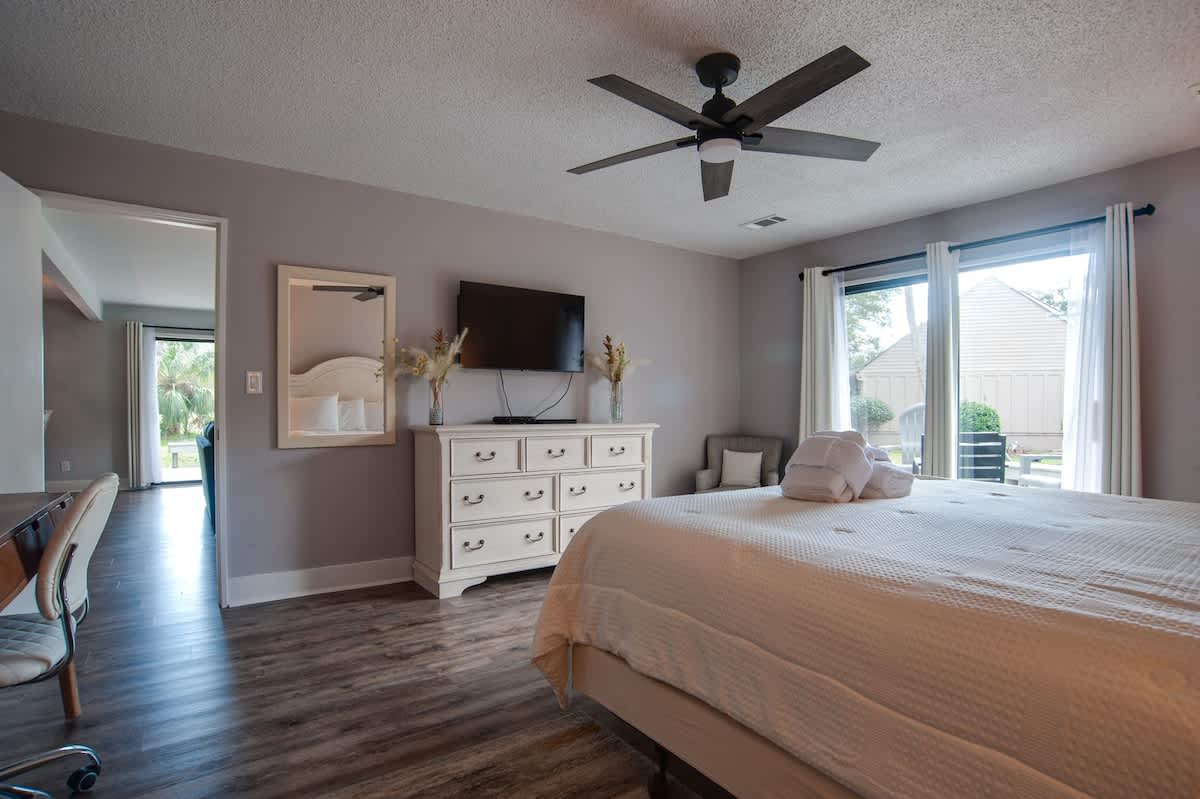 Drift off in your peaceful bedroom with a gentle ceiling fan and natural light streaming through large windows.