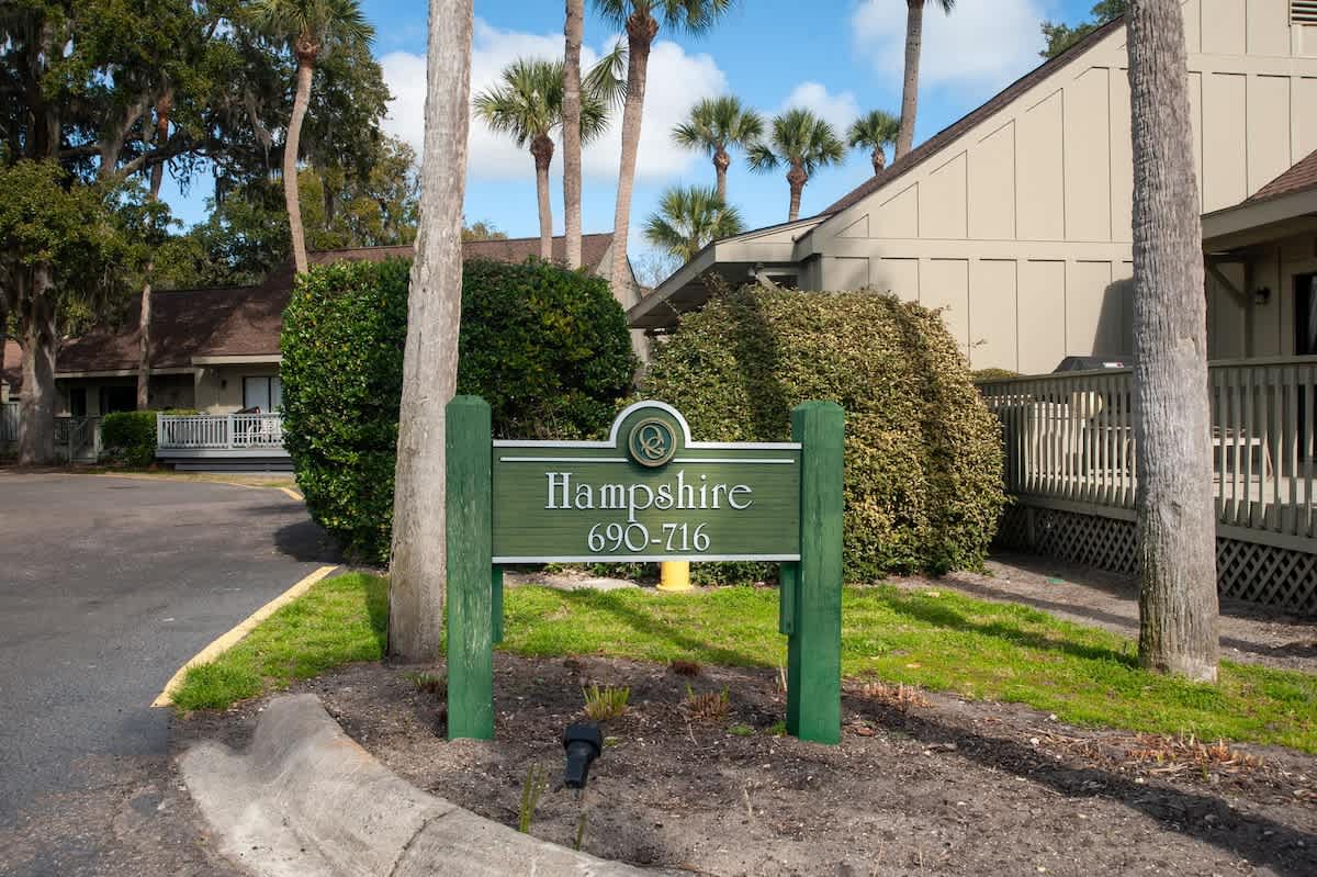 Hampshire complex entrance with tropical palm trees and well-maintained landscaping welcomes guests to this coastal property.