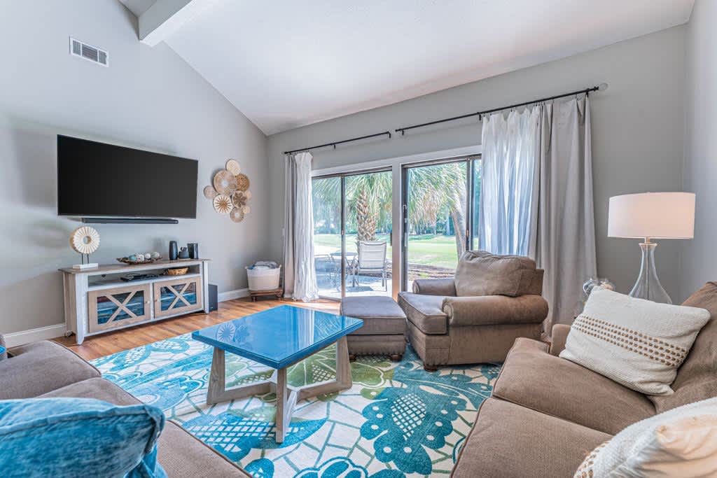 Relax in your bright living space with comfy seating, vibrant coastal décor, and tropical views through sliding glass doors.