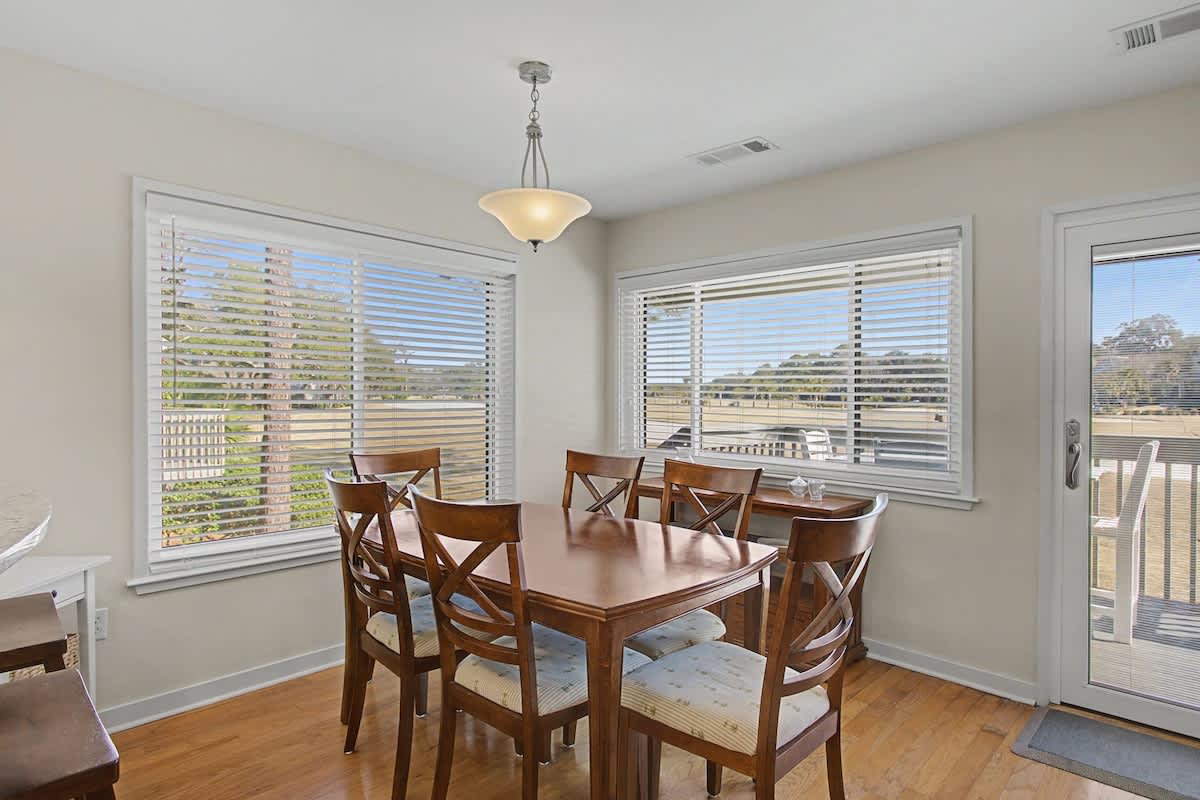Gather around this warm dining space where natural light streams through multiple windows, creating the perfect setting for memorable meals together.
