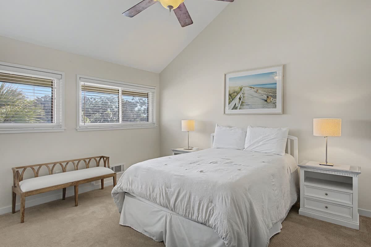 Drift into peaceful slumber in your serene bedroom, complete with plush linens, gentle coastal artwork, and a ceiling fan for perfect comfort.