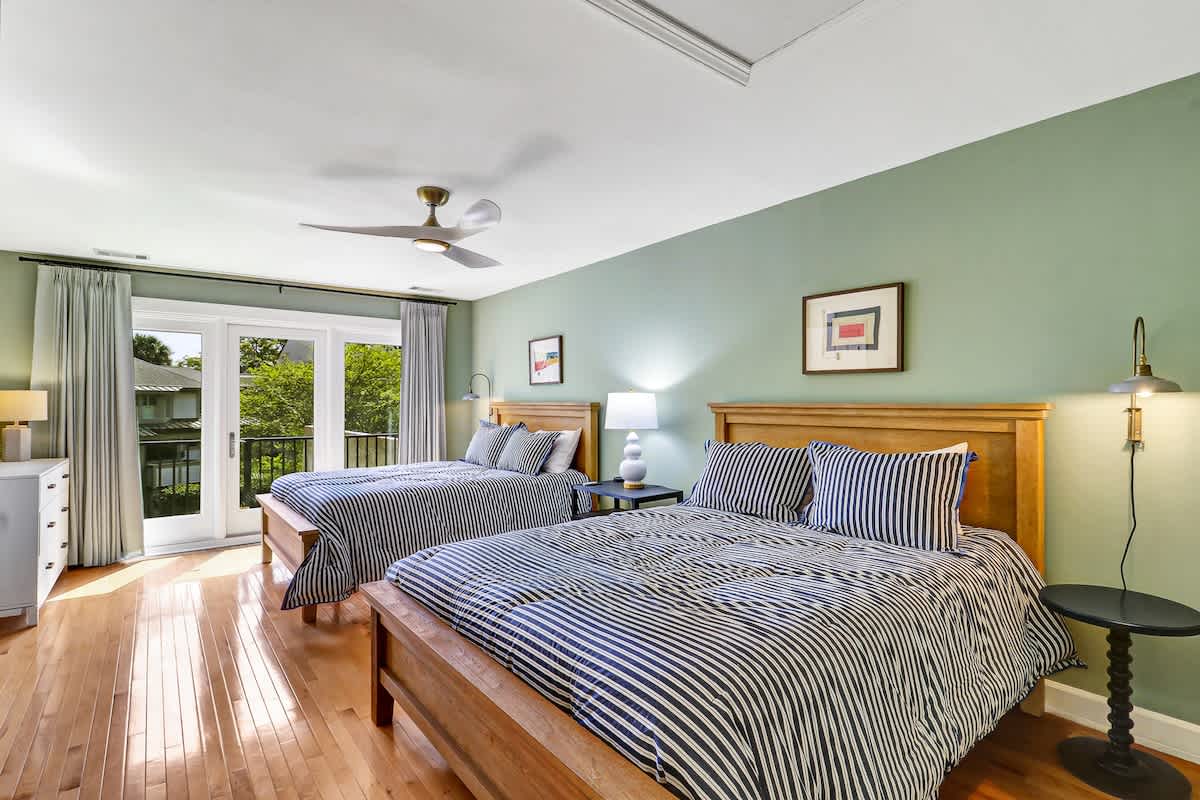 Unwind in your tranquil bedroom with twin beds, where soft green walls and striped bedding create a peaceful retreat after exploring.