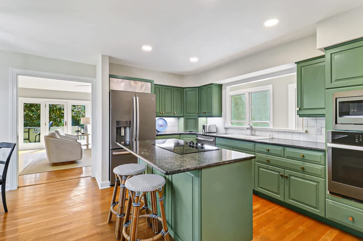 Your spacious kitchen features stunning sage-green cabinets, granite countertops, and modern stainless steel appliances - perfect for creating memorable meals together.