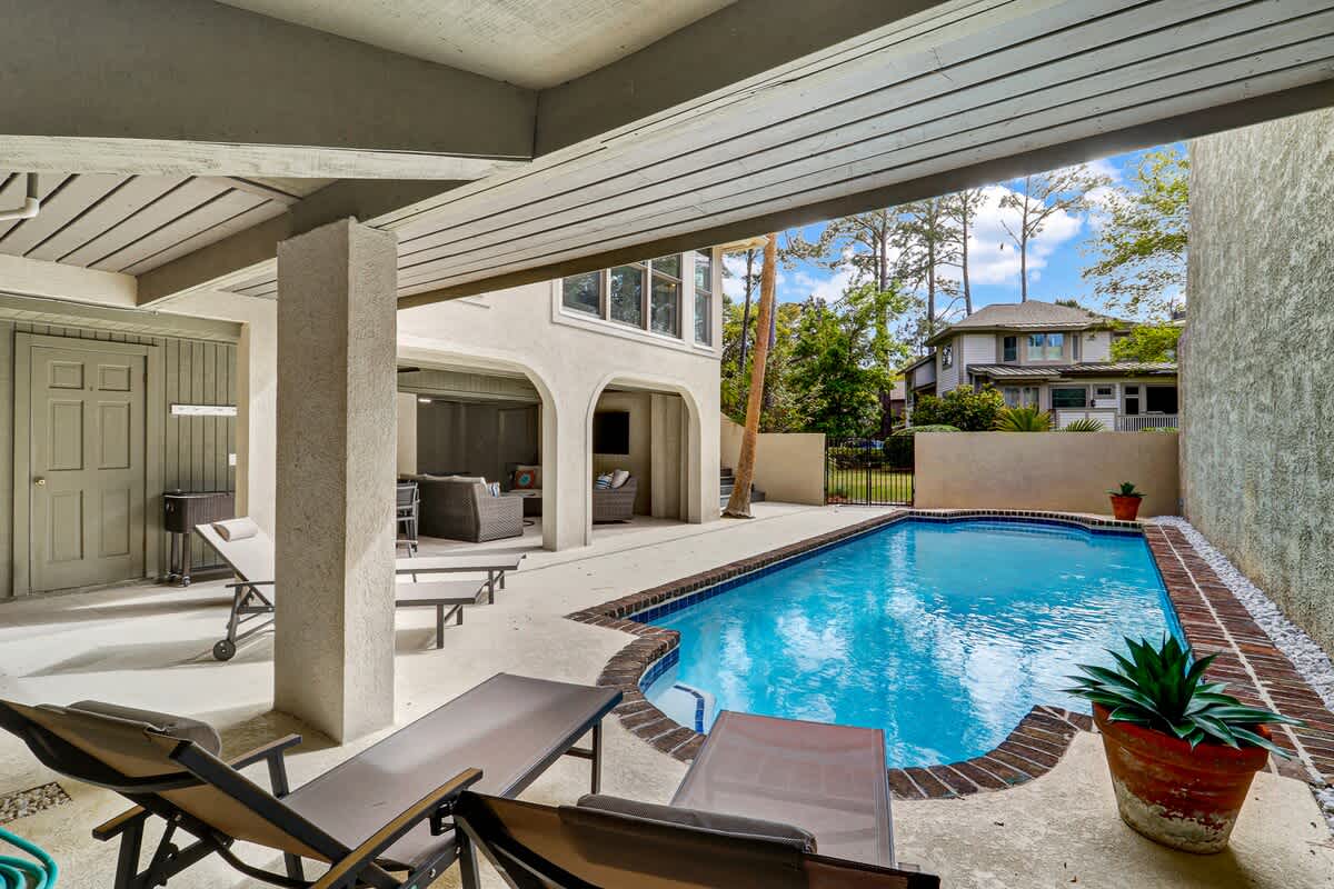 Expansive pool area with covered patio seating, multiple lounging spaces, and a private deck, offering comfort and flexibility for outdoor living and entertaining.