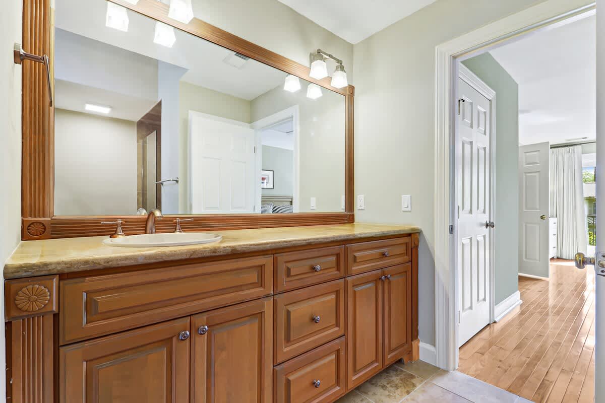 Step into your elegant bathroom featuring rich wood cabinetry, granite counters, and bright vanity lighting for your morning routine.