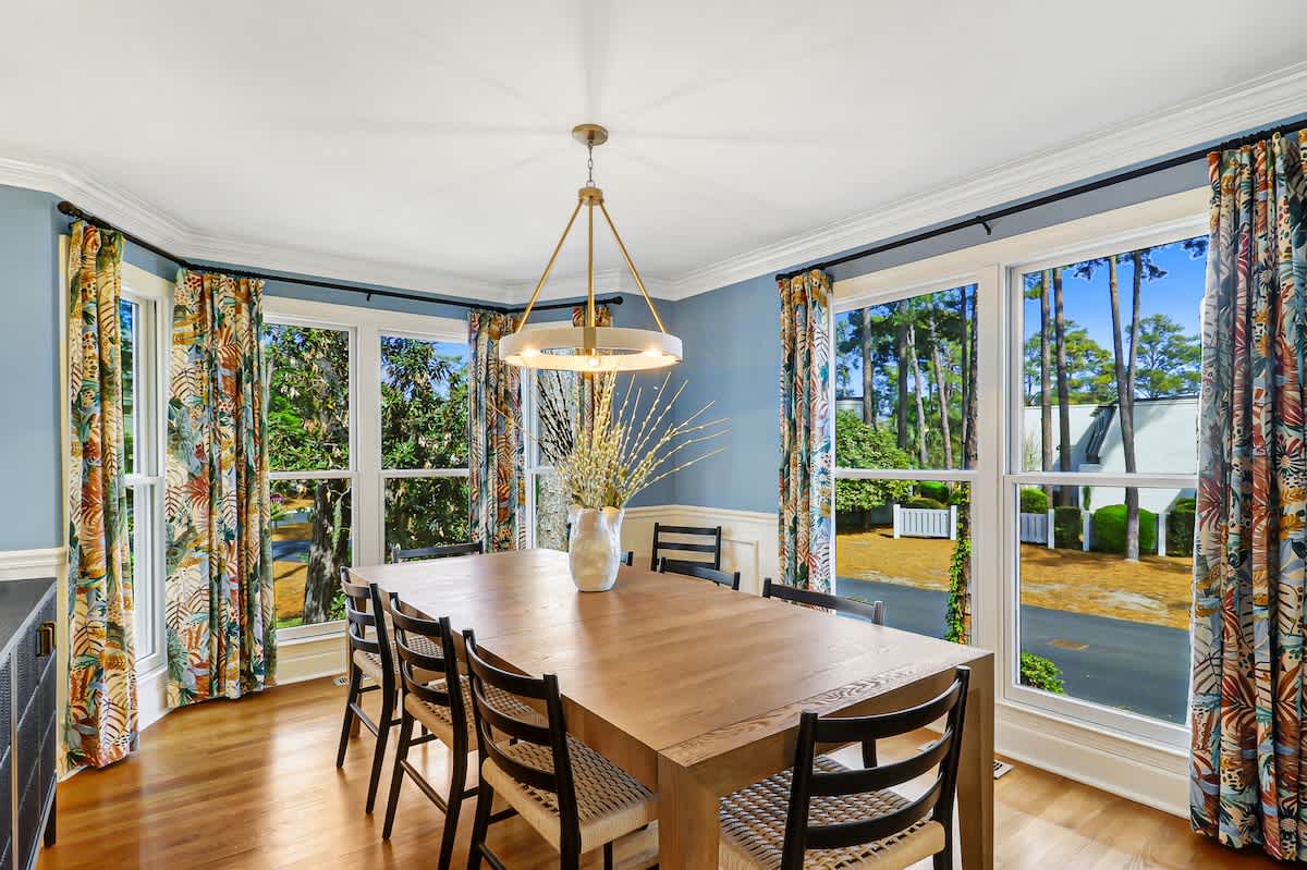Gather around your elegant dining table where tropical curtains frame garden views and warm light creates perfect moments for memorable meals together.