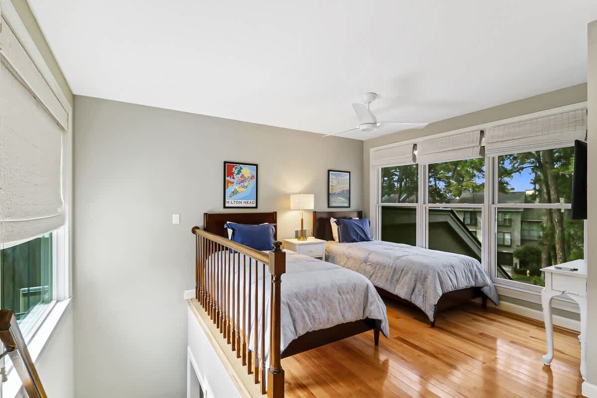 Relax in your bright bedroom with twin beds, hardwood floors, and peaceful tree views from large windows.