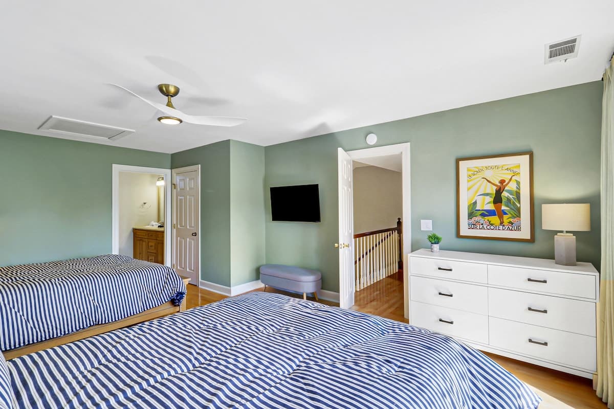 Relax in your serene bedroom with twin beds featuring crisp nautical bedding and coastal artwork setting a peaceful mood.