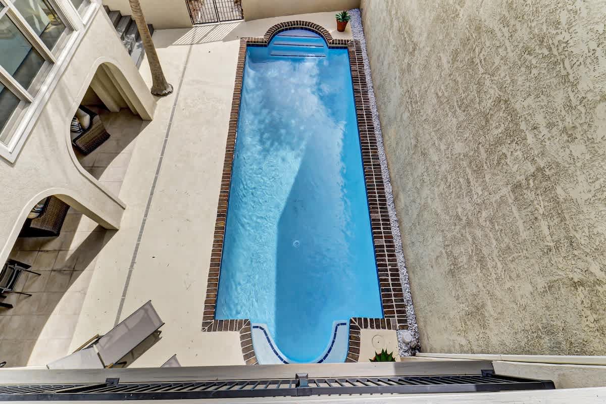 Aerial view of the property's private swimming pool and outdoor terrace area with decorative brick tile edging.