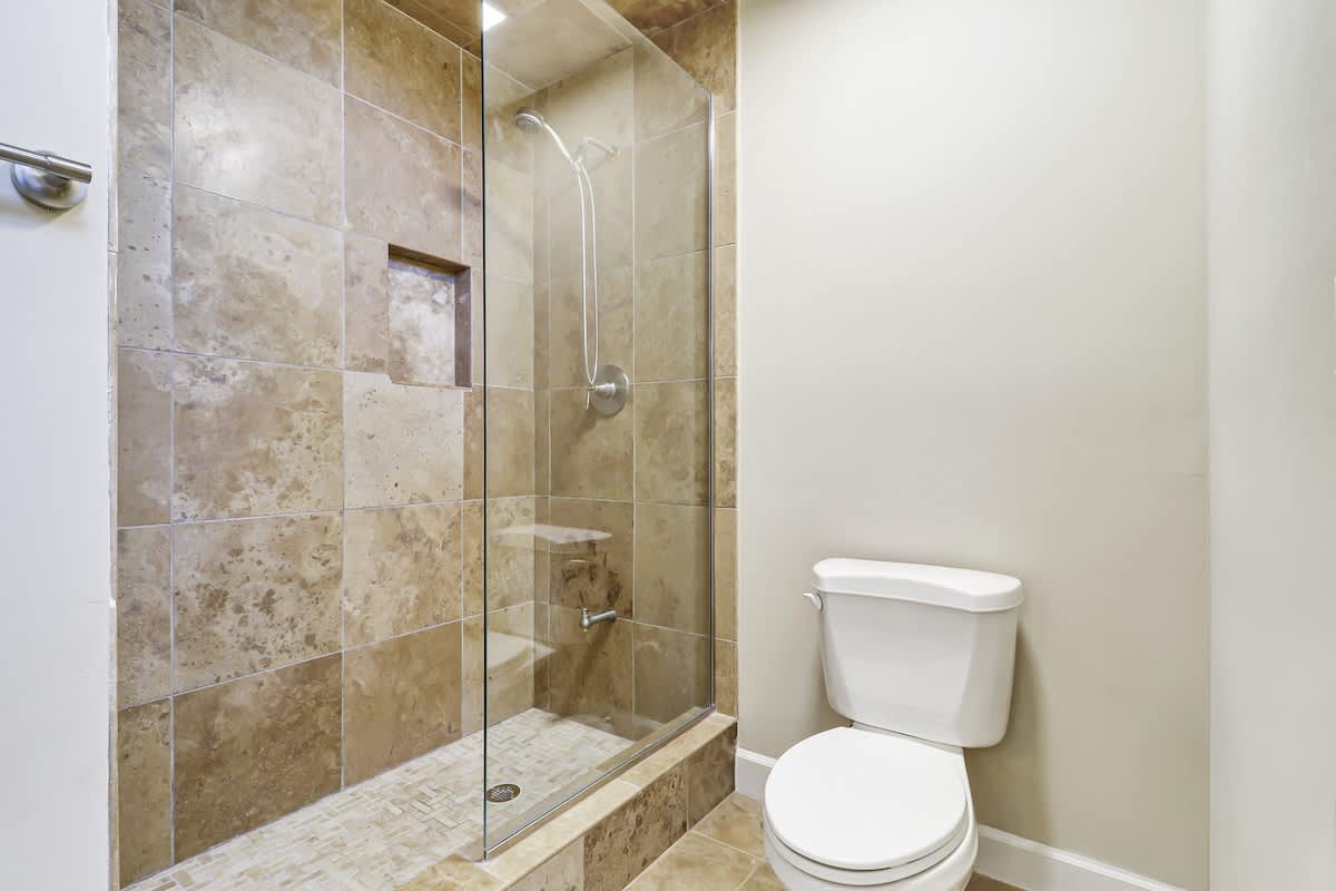 Your private bathroom features elegant travertine tiles and a spacious walk-in shower with modern glass doors for a luxurious retreat.