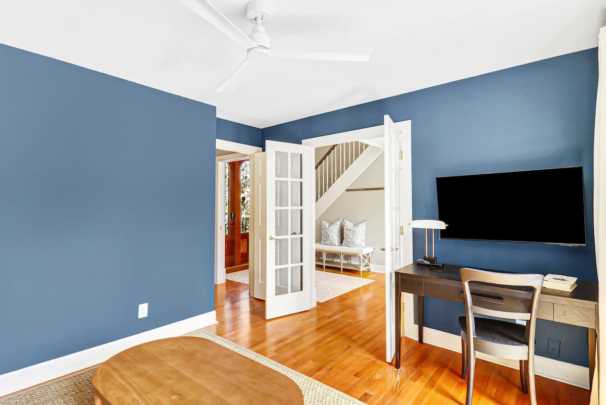 Your private workspace features calming blue walls, rich hardwood floors, and French doors opening to a serene sitting area.