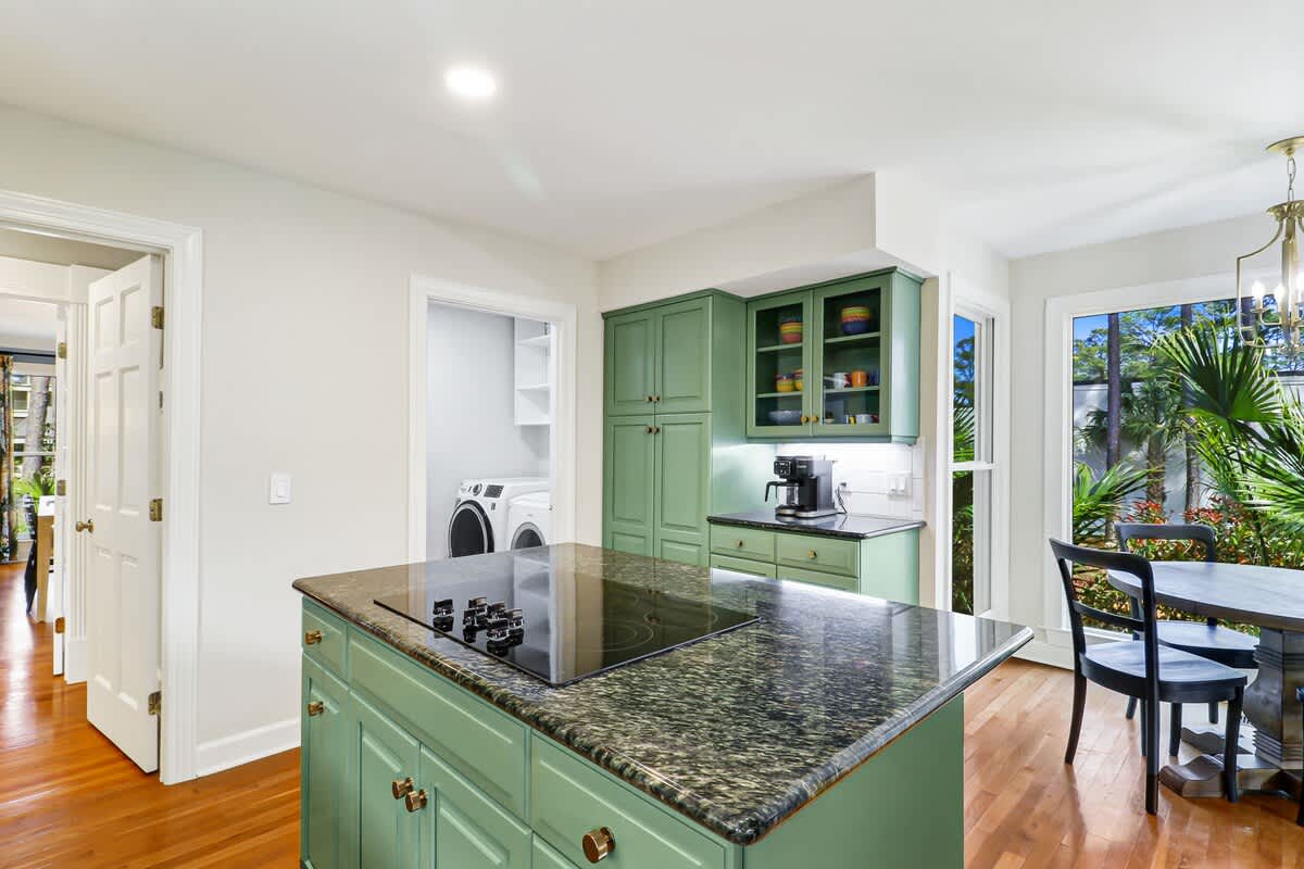 Functional kitchen island with granite counters and sage-green cabinetry creates the perfect space for meal prep and morning coffee.