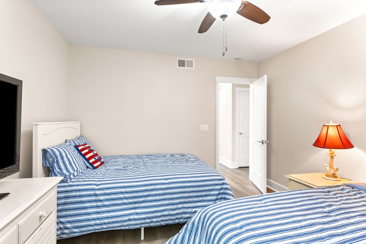 Your cheerful bedroom features double beds with nautical striped linens and warm lighting for restful nights.