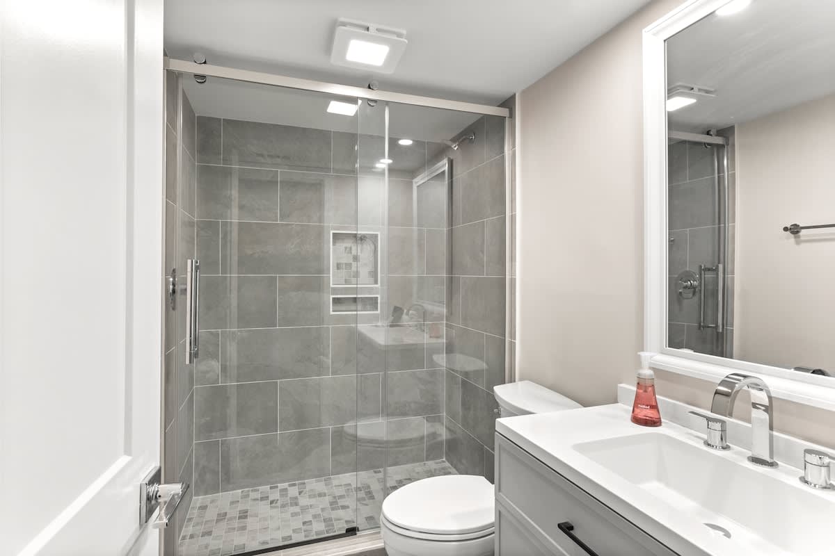 Step into your sleek modern bathroom with a spacious walk-in shower featuring elegant gray tile and glass doors for a spa-like experience.