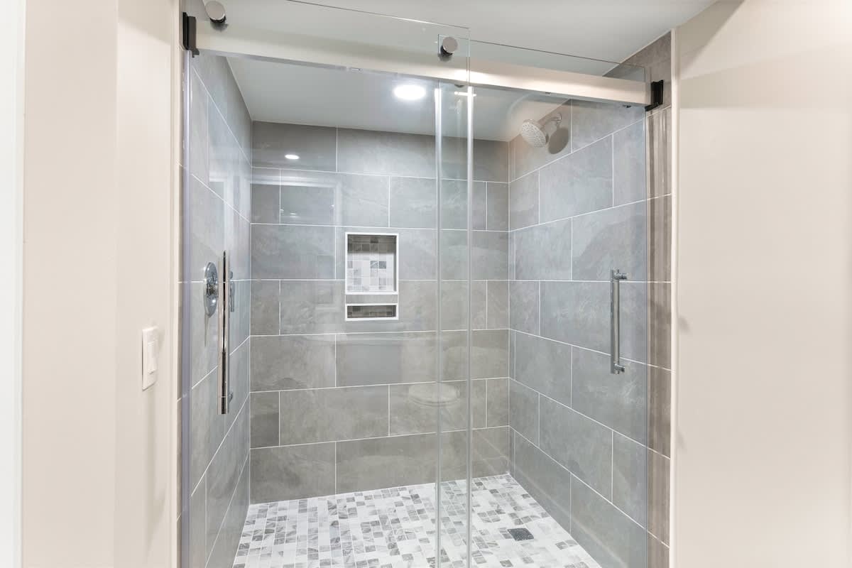 Step into your sleek glass-enclosed shower with rainfall head and modern tiles for your perfect morning refresh.