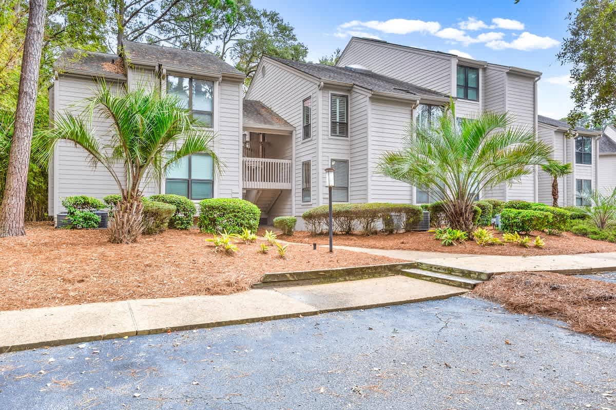 Modern residential buildings nestled among mature trees with tropical palm landscaping and well-maintained grounds.