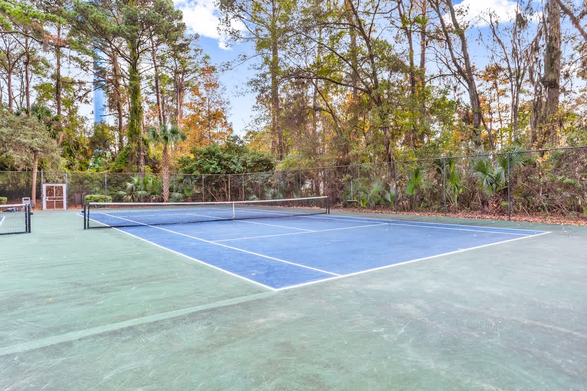 Tennis court surrounded by lush tropical foliage, providing a private recreational setting on the property grounds.