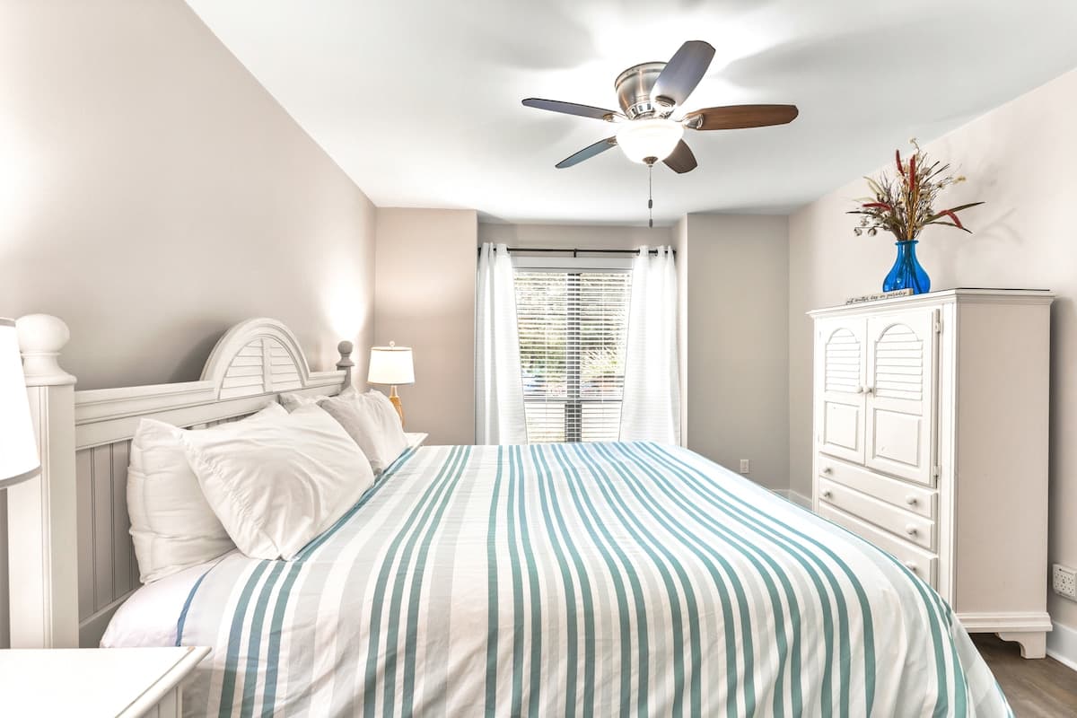 Drift off in your coastal-inspired retreat with soft linens, gentle ceiling fan breeze, and soothing seaside colors.