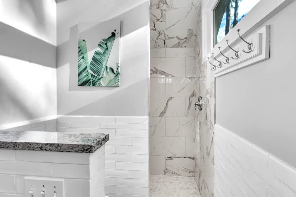 Your luxurious marble shower awaits with elegant finishes and tropical artwork creating a spa-like retreat.