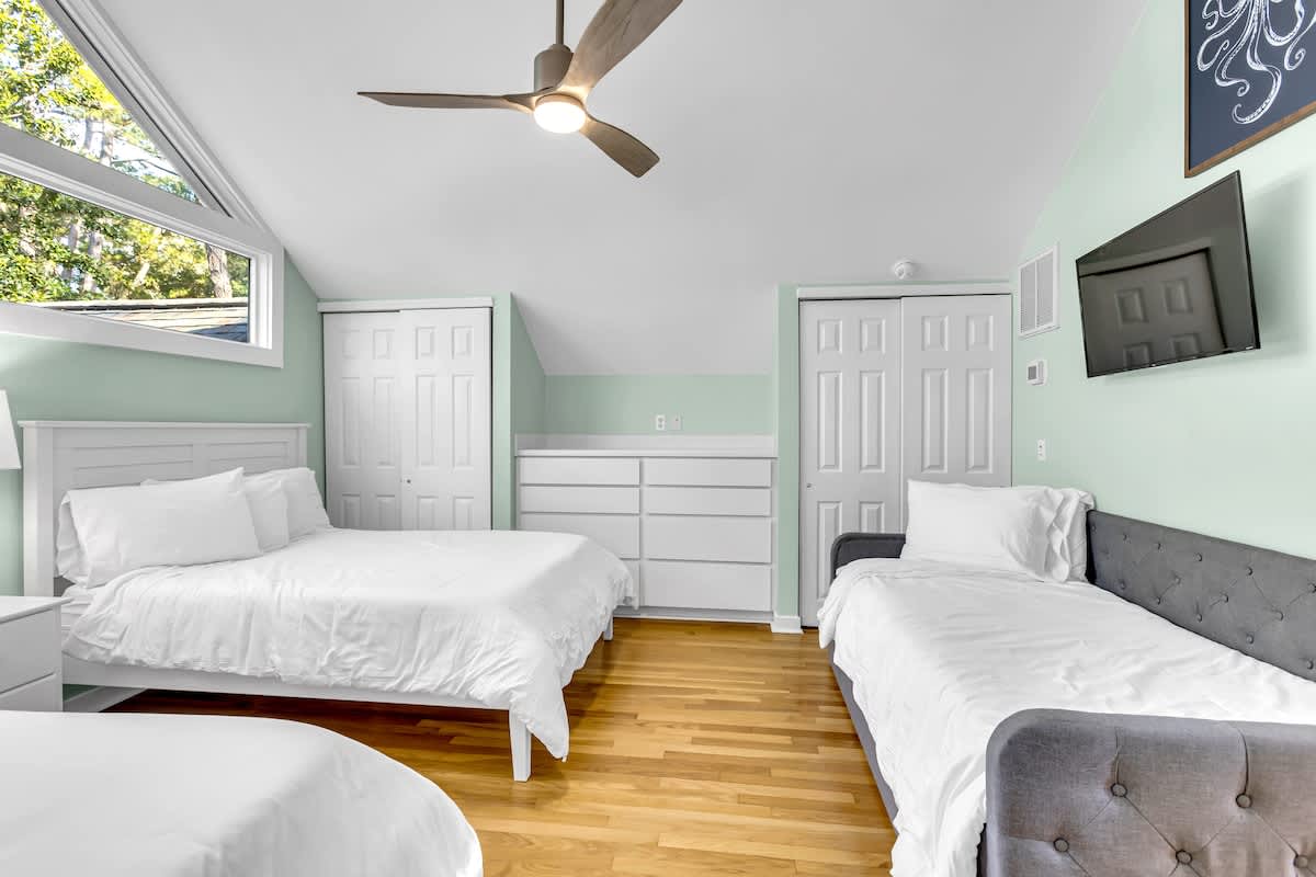Rest peacefully in your spacious bedroom with crisp linens, natural light, and climate comfort from the ceiling fan above.