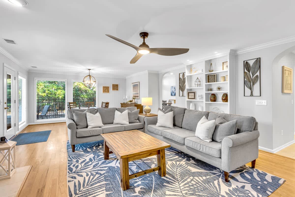 Unwind in your spacious living room with plush gray sofas, stylish built-ins, and peaceful pool views