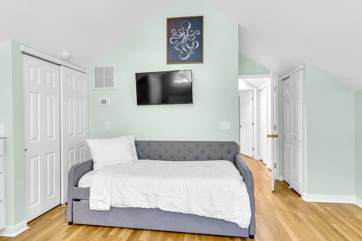Relax in your tranquil bedroom featuring a cozy daybed, wall-mounted TV, and soothing mint green walls that create the perfect retreat.