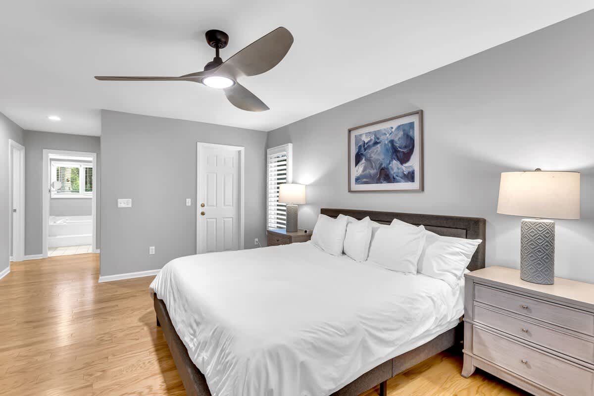 Drift off to sleep in your serene bedroom featuring crisp linens, warm hardwood floors, and gentle ceiling fan breeze.