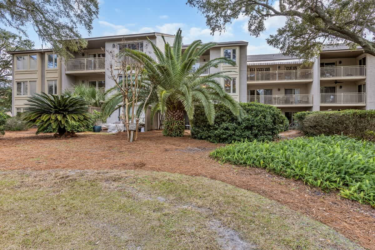 Multi-story vacation property surrounded by tropical landscaping and mature palm trees in a peaceful residential setting.