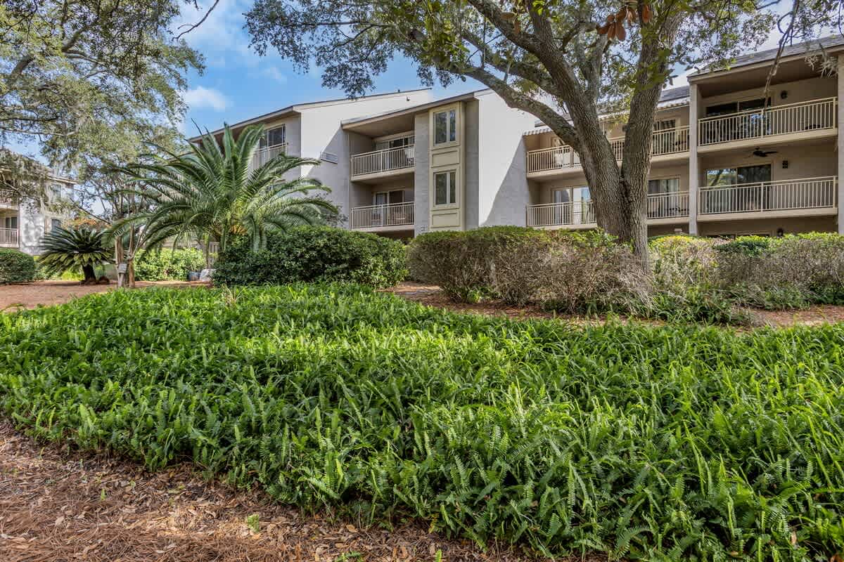 Multi-level property building surrounded by lush tropical landscaping and mature trees in a peaceful resort setting.