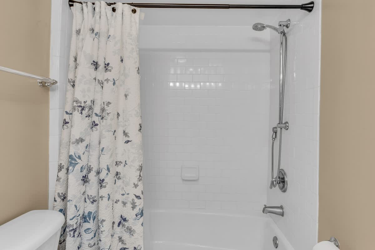 Refresh in your private bathroom featuring a gleaming tub-shower combo with elegant floral curtain and modern fixtures.