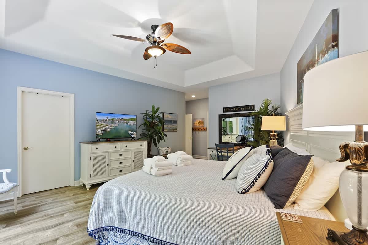 Sink into your plush coastal bedroom with crisp linens, gentle ceiling fan, and charming decor creating the perfect retreat.