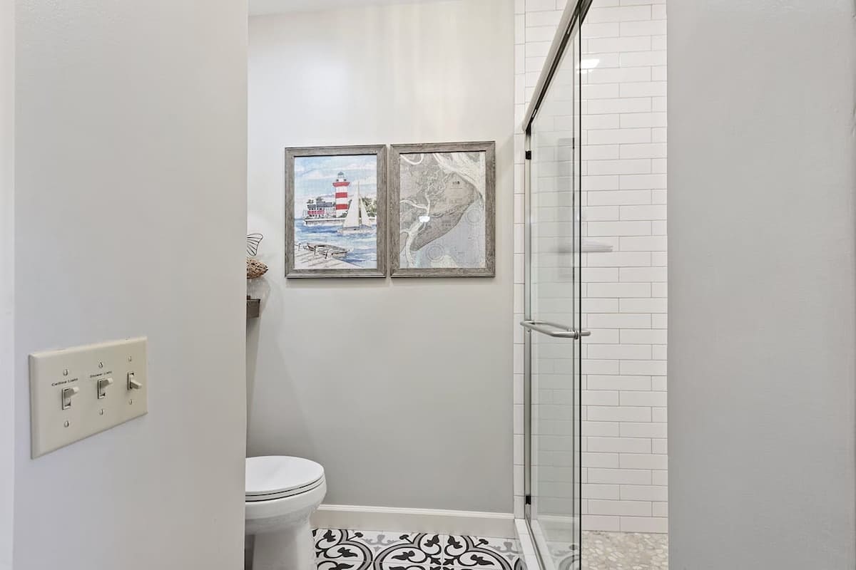 Step into your modern bathroom retreat with elegant subway tile shower and coastal artwork creating a serene atmosphere.