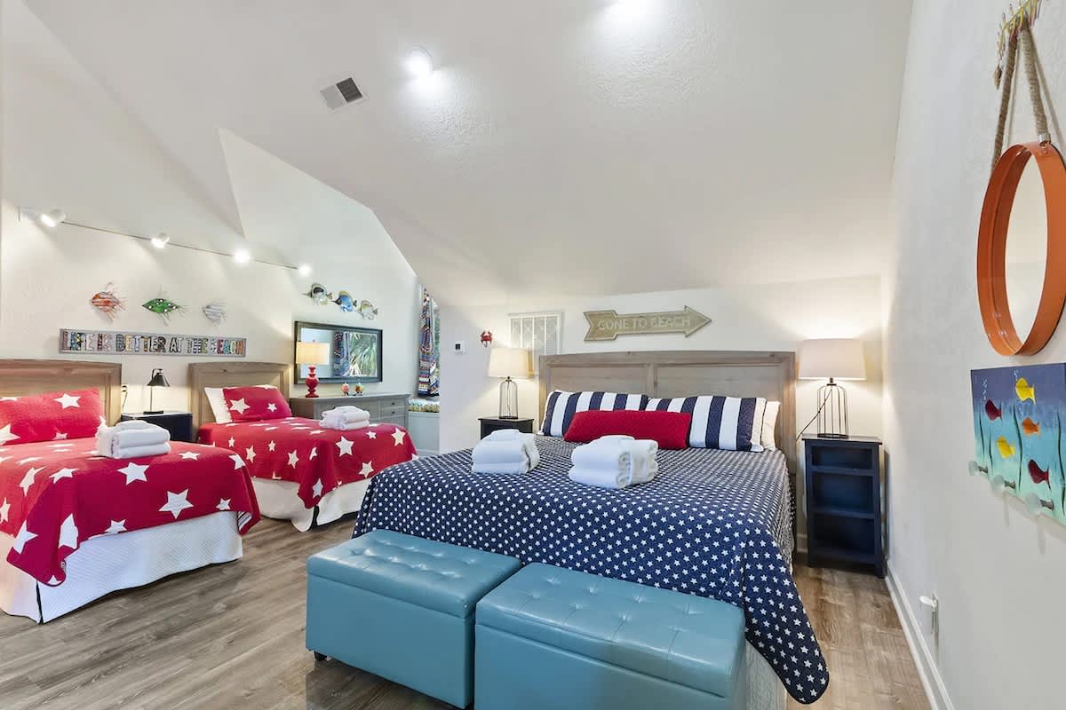 Step into your cheerful nautical-themed bedroom where starry red bedding and navy stripes create the perfect coastal retreat for restful nights.