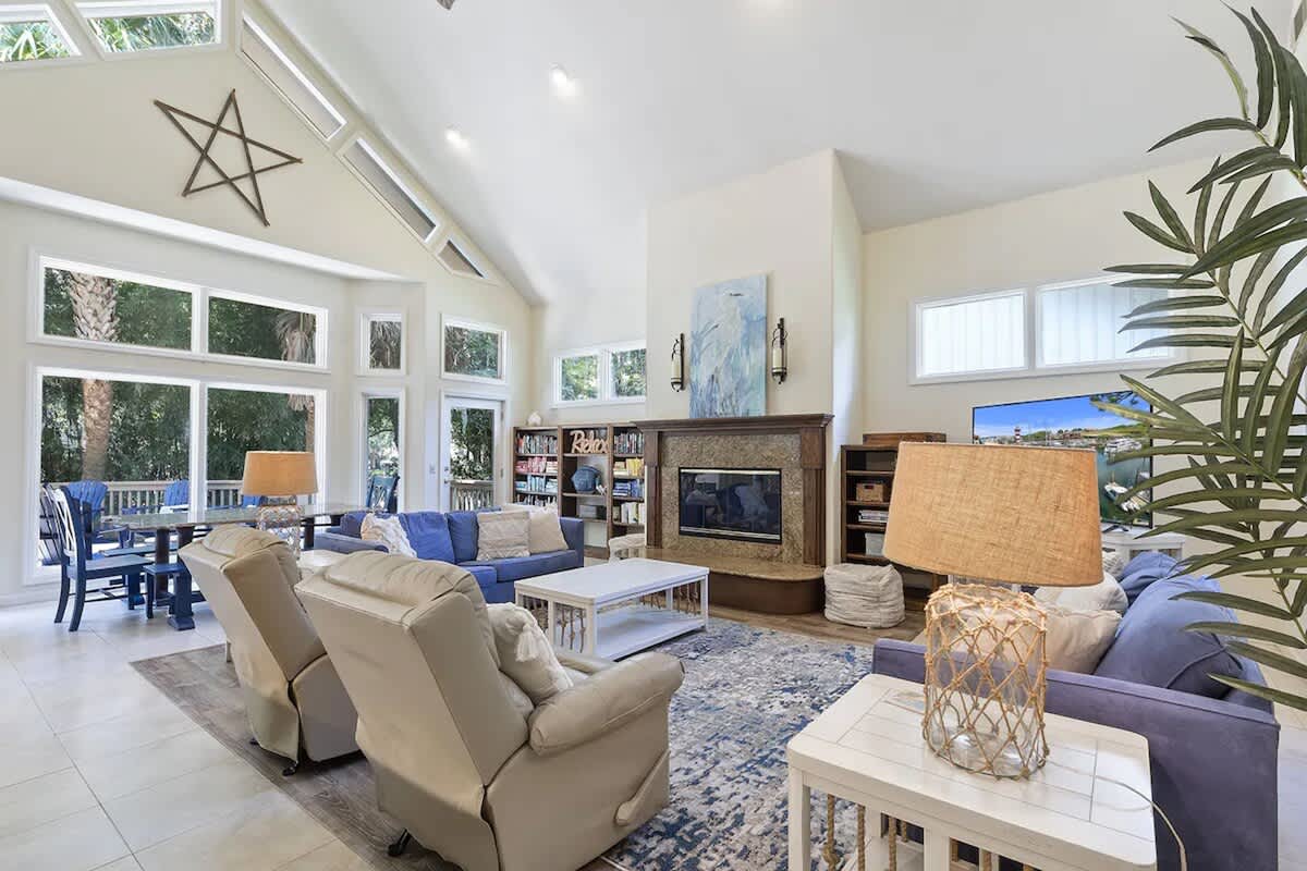 Your spacious living room welcomes you with soaring ceilings, natural light flooding through expansive windows, and plush seating around a cozy fireplace.