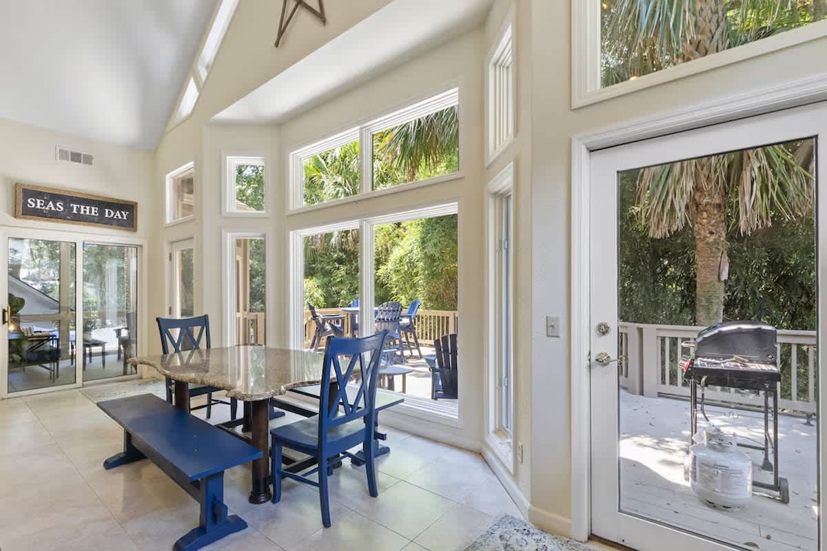 Gather around your sunlit dining table where coastal charm meets comfort, with sliding doors opening to your private deck.