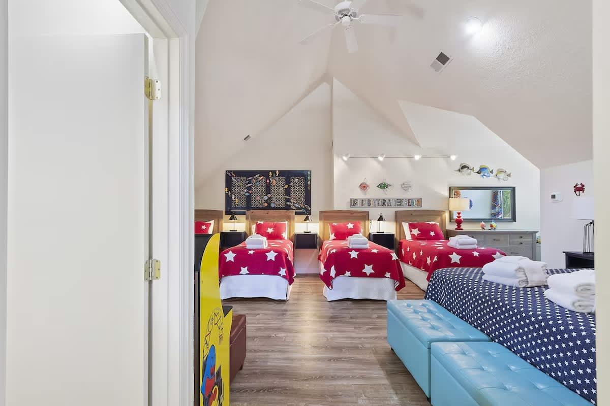 Your family will love this vibrant attic bedroom with star-patterned bedding, custom lighting, and cozy entertainment setup.