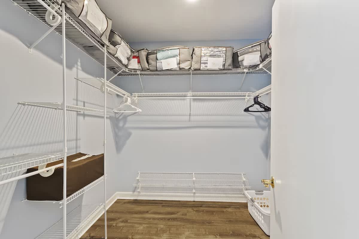 Your private walk-in closet offers generous storage with wire shelving, hanging space, and a convenient laundry basket for effortless organization.