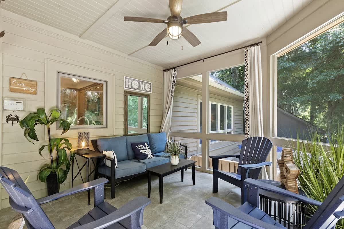 Unwind on your screened porch with comfortable seating and ceiling fan, perfect for morning coffee or evening relaxation.
