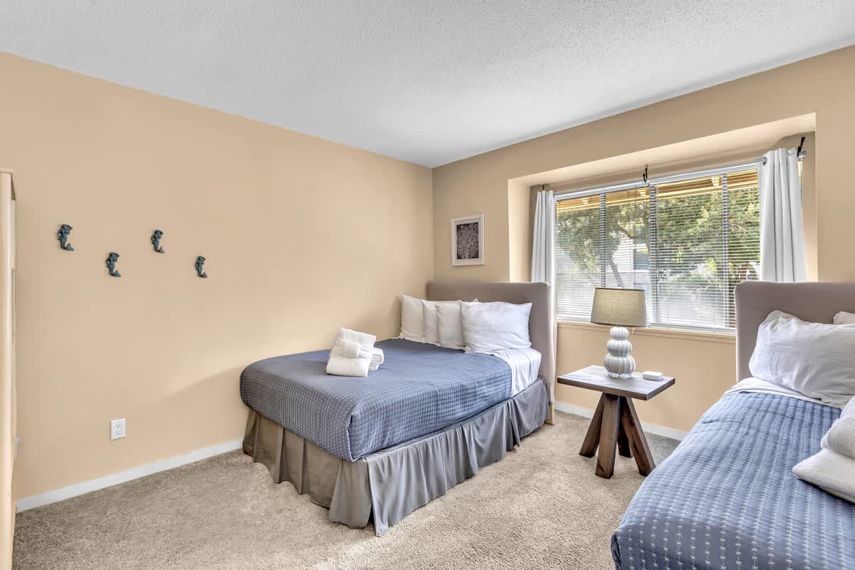 Drift off peacefully in your cozy twin bedroom, where soft blue linens and warm natural light create the perfect restful retreat.
