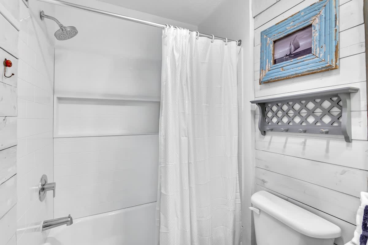 Step into your bright, nautical-themed bathroom featuring a spacious shower-tub combo with coastal charm.