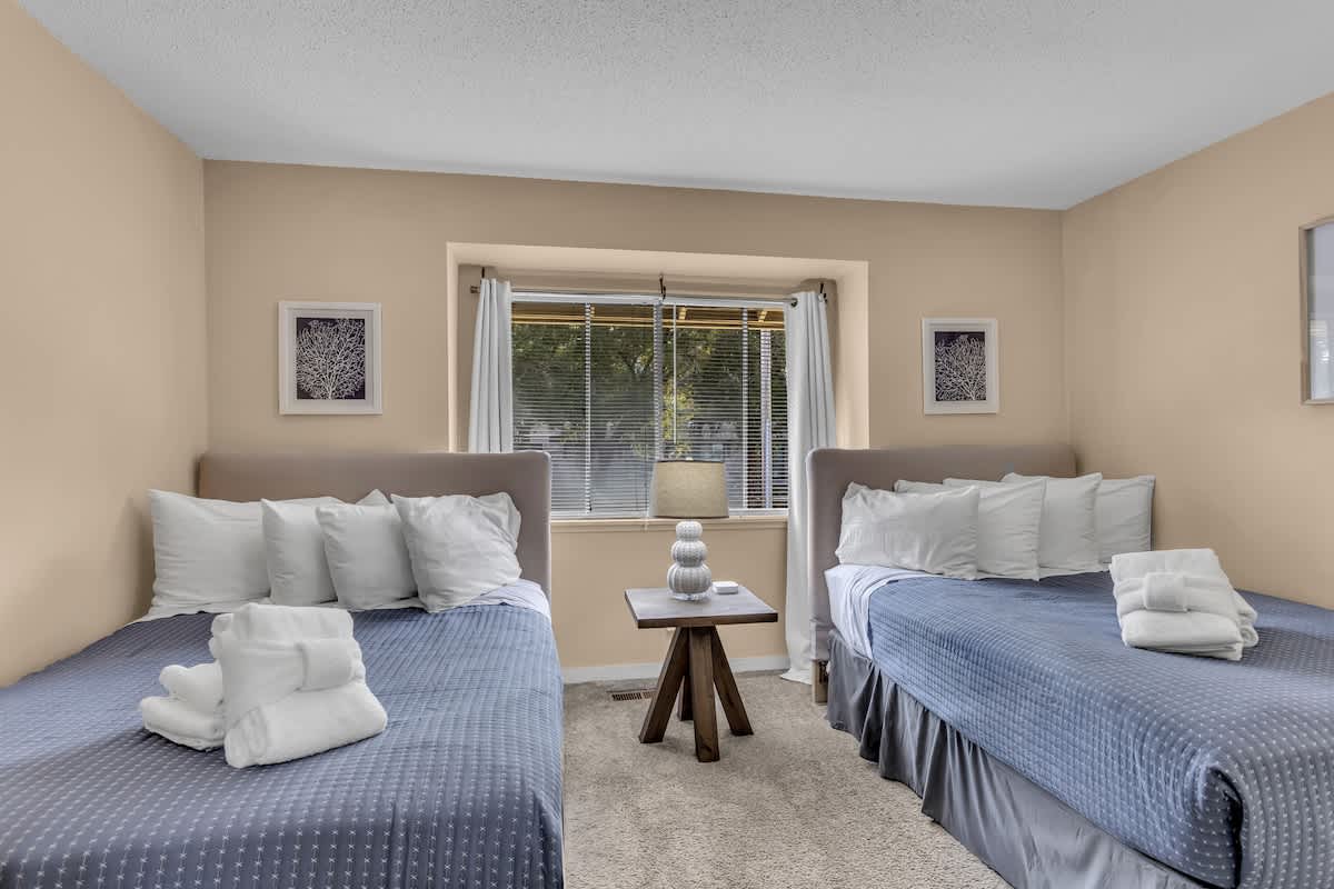 Rest peacefully in your twin bed setup, complete with plush towels and soft blue linens in this sunny, well-appointed room.