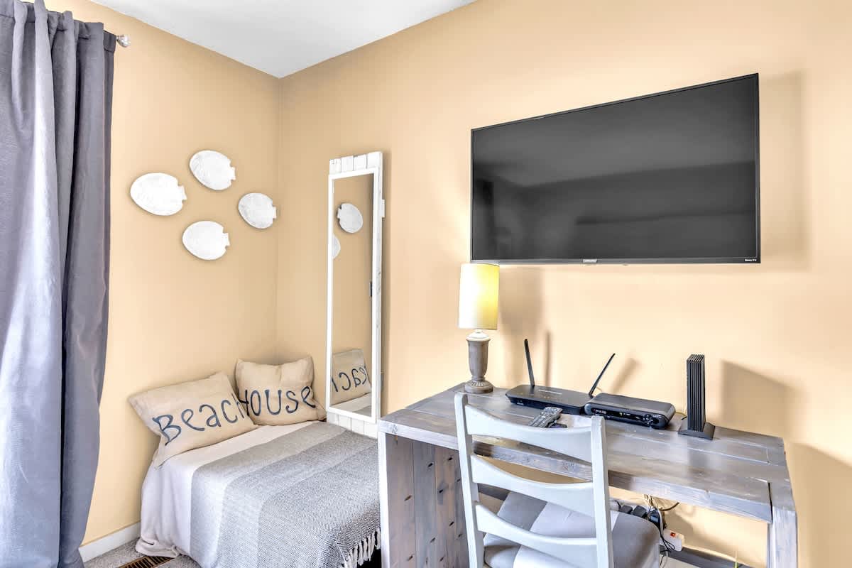 Settle into your cozy retreat with beach-themed décor, flat-screen TV, and charming work nook bathed in warm natural light.