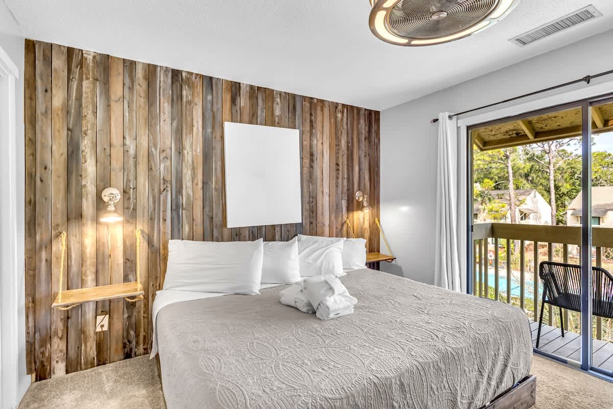 Drift off in your cozy bedroom featuring rustic wood accents, crisp linens, and a private balcony overlooking the pool.