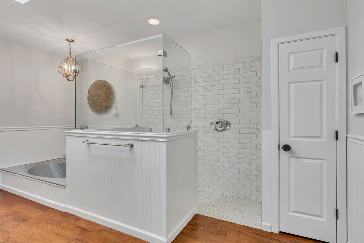 Unwind in your elegant bathroom featuring a luxurious soaking tub and spacious glass-enclosed shower with classic subway tile.