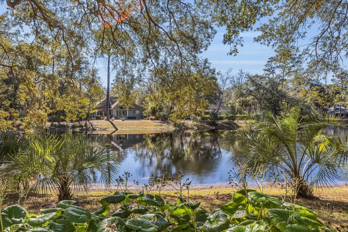 Peaceful lakefront property nestled among mature trees with tropical landscaping and tranquil water views.