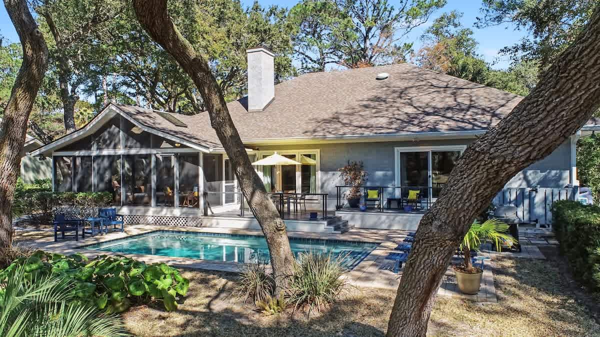 Private oasis featuring a sparkling pool surrounded by mature trees and comfortable outdoor seating for your perfect getaway.
